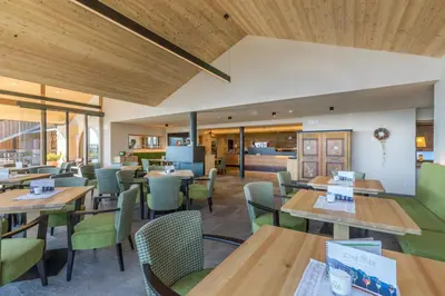 a restaurant with wooden ceilings and tables and chairs at Berghotel Schlemmer in Bressanone