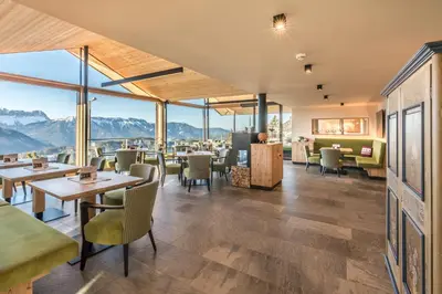 a restaurant with tables and chairs and mountains in the background at Berghotel Schlemmer in Bressanone