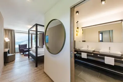 a bedroom with a bed and a couch and a table at Oliven- & Genusshotel Hirzer in Schenna