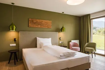 a bedroom with a white bed and a pink chair at Oliven- & Genusshotel Hirzer in Schenna