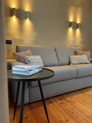 a living room with a couch and a table with books at ADAM Suites - Brixen Card included in Bressanone