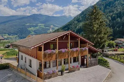 a house in the mountains with flowers on the balcony at Chalet Rasteck in Campo Tures