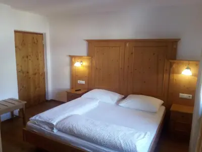 a bedroom with a large white bed with wooden walls at Chalet Rasteck in Campo Tures
