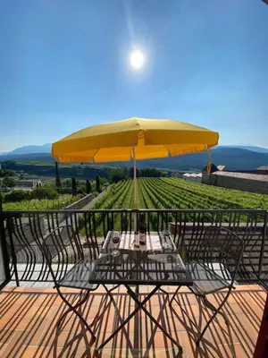 a table and chairs with a yellow umbrella on a deck at Gästehaus Anna in Caldaro
