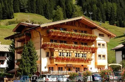 a large building with flowers on the side of it at Hotel Garni San Nicolò in Pozza di Fassa