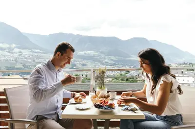 a man and woman sitting at a table with a plate of food at Apartment Ruprecht in Tirolo