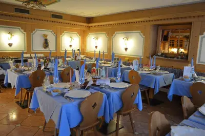 a room with tables and chairs with blue tablecloths at Hotel Stella Alpina in Moena