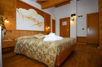 a bedroom with a large bed with a large painting on the wall at Hotel Stella Alpina in Moena