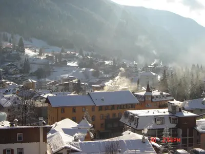 a city with snow covered buildings and a mountain at Hotel Stella Alpina in Moena