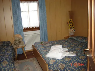 a bedroom with two beds and a teddy bear at Hotel Stella Alpina in Moena
