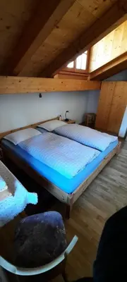 a bedroom with two beds and a chair in a attic at Hof am Brunnen Mansarde in Cornaiano