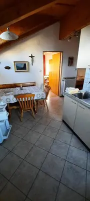 a living room with a table and a kitchen at Hof am Brunnen Mansarde in Cornaiano