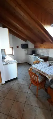 a room with a table and a kitchen with a table and chairs at Hof am Brunnen Mansarde in Cornaiano