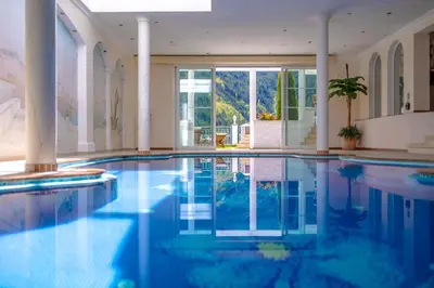 a swimming pool with blue water in a building at Das Land-Palais - Your lovely Mountain Hideaway in Selva dei Molini