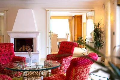 a living room with red chairs and a glass table at Das Land-Palais - Your lovely Mountain Hideaway in Selva dei Molini