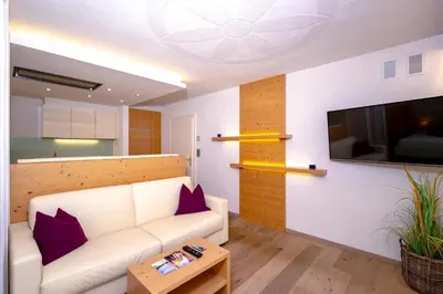 a living room with a white couch and a flat screen tv at Das Land-Palais - Your lovely Mountain Hideaway in Selva dei Molini