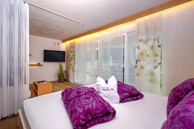 a bedroom with a white bed with purple pillows at Das Land-Palais - Your lovely Mountain Hideaway in Selva dei Molini