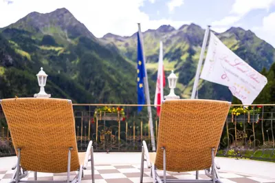 two chairs sitting on top of a balcony with flags at Das Land-Palais - Your lovely Mountain Hideaway in Selva dei Molini
