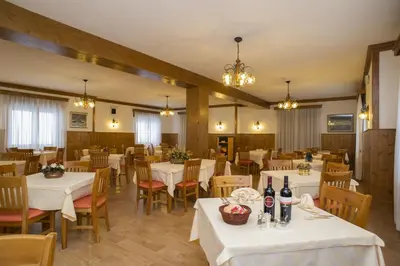 a restaurant with white tables and chairs and lights at Hotel Villa Ines in Borca di Cadore