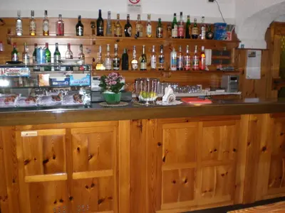 a bar with wooden cabinets and bottles of alcohol at Hotel Villa Ines in Borca di Cadore