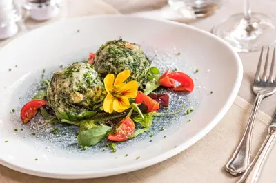 a plate of food with meat and vegetables on a table at Hotel Brunella in San Vigilio Di Marebbe