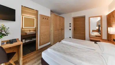 a bedroom with a bed and a table and a desk at Hotel Brunella in San Vigilio Di Marebbe