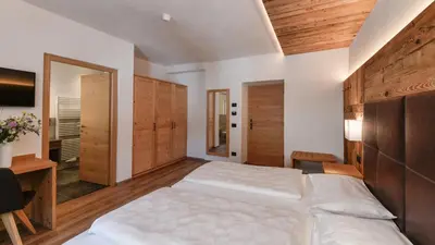 a bedroom with a large white bed and wooden cabinets at Hotel Brunella in San Vigilio Di Marebbe
