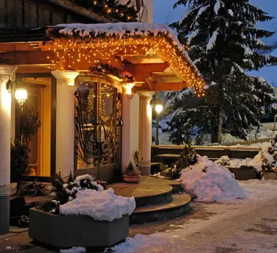 a house with christmas lights on it in the snow at Hotel Brunella in San Vigilio Di Marebbe