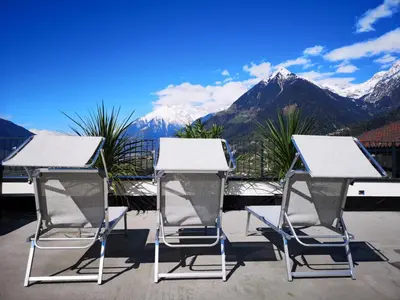 two chairs and a table with mountains in the background at Antonya Apartments in Schenna