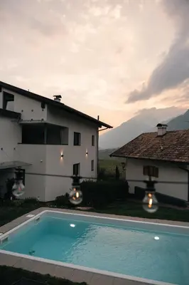 a villa with a swimming pool in front of a house at Antonya Apartments in Schenna