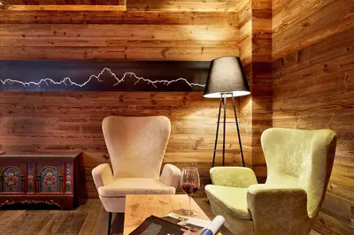 two chairs and a table in a room with wooden walls at Naturhotel Die Waldruhe GmbH in Chienes