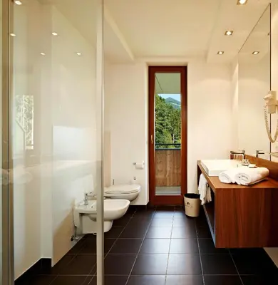 a bathroom with a toilet and a sink and a shower at Naturhotel Die Waldruhe GmbH in Chienes