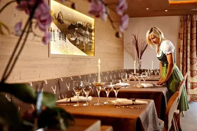 a woman standing in front of tables with wine glasses at Naturhotel Die Waldruhe GmbH in Chienes