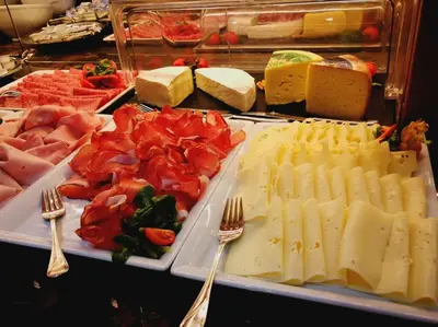 a display of cheese and meats on a table with forks at Wellness Hotel Gran Risa***S in La Villa
