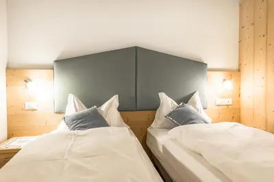 a bedroom with two beds and a large headboard at Garni Tyrolia in Campitello di Fassa