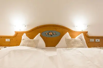 a bedroom with two beds with white sheets and pillows at Garni Tyrolia in Campitello di Fassa