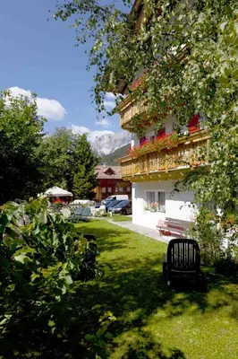 a bench sitting in the grass next to a building at Garni Tyrolia in Campitello di Fassa