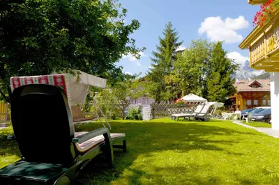a yard with a chair sitting in the grass at Garni Tyrolia in Campitello di Fassa