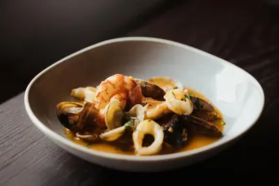 a white bowl of food with shrimp and calamari at Hotel Jägerhof in Colfosco