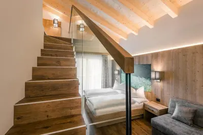 a bedroom with a staircase and a bed and a couch at Hotel Jägerhof in Colfosco