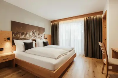 a bedroom with a large bed and a window at Hotel Jägerhof in Colfosco