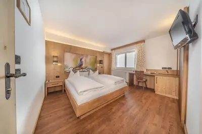 a bedroom with a large white bed and a television at Hotel Jägerhof in Colfosco