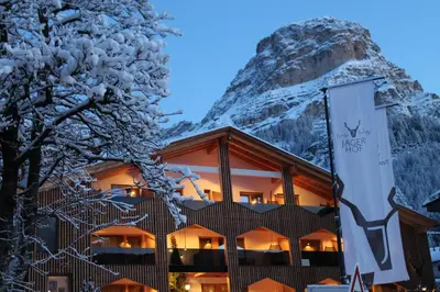 a hotel with a snow covered mountain in the background at Hotel Jägerhof in Colfosco