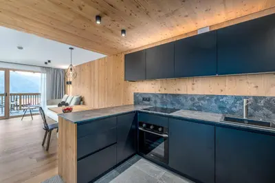 a kitchen with dark blue cabinets and a table at SUMMERER - Living Nature - Apartments with private SPA in Bressanone