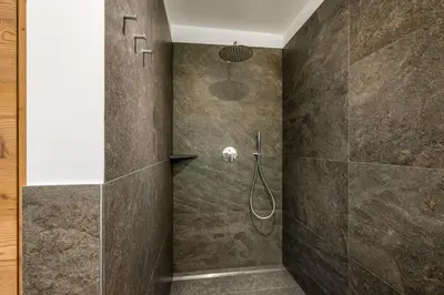 a bathroom with a shower with brown tiles at SUMMERER - Living Nature - Apartments with private SPA in Bressanone