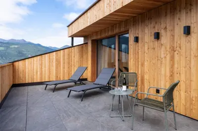 a patio with chairs and a table on a building at SUMMERER - Living Nature - Apartments with private SPA in Bressanone