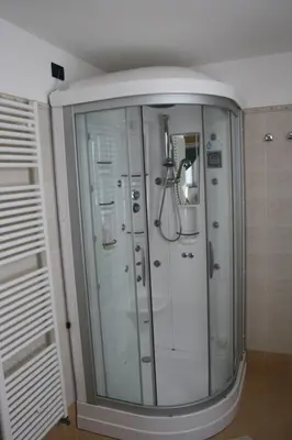a shower in a bathroom with white cabinets at La Baita in Livinallongo del Col di Lana