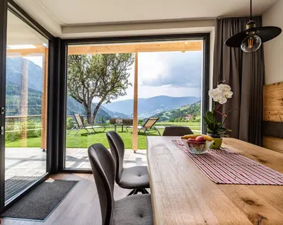 a dining room with a table and a large window at Apartments Grunnes in Ortisei