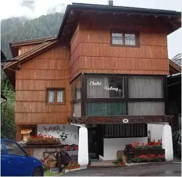 a wooden building with flowers in front of it at Chalet Valeruz in Canazei