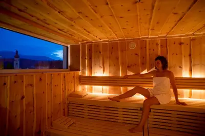 a woman is sitting in a sauna at Parc Hotel Tyrol in Castelrotto